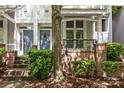 Townhome exterior featuring covered front porch and brick accents, with shade from a mature tree at 625 N Alexander St, Charlotte, NC 28202
