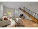 Bright, staged living room with hardwood floors, modern staircase, and large windows at 625 N Alexander St, Charlotte, NC 28202