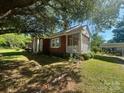 Quaint brick home featuring a screened-in porch and lush greenery in a peaceful setting at 6585 White St, Kershaw, SC 29067