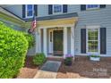 Close-up view of the home's entry showcasing its well-kept landscaping, flowers, and American flag at 9209 Cameron Wood Dr, Charlotte, NC 28210