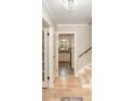 Bright hallway with hardwood floors leading to the kitchen and stairs featuring white trim and grey paint at 118 Spicewood Cir, Troutman, NC 28166