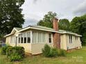 Single story home with vinyl siding, brick chimney, a green metal roof and several windows at 1703 Lowder St, Albemarle, NC 28001
