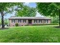 Charming single-story brick home with a lush green lawn and mature trees creating a welcoming curb appeal at 174 Wintergreen Cir, Statesville, NC 28677