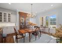 Sunlit dining room with a classic chandelier, hardwood floors, and a large window overlooking the yard at 2309 Ethan Way, Weddington, NC 28104
