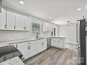 Bright updated kitchen with stainless steel appliances, white cabinets, granite countertops, and modern gray-toned flooring at 2544 Cedarwild Rd, Charlotte, NC 28212