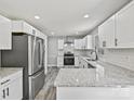 Modern kitchen featuring stainless steel appliances, white cabinets, granite countertops, tile backsplash, and stylish flooring at 2544 Cedarwild Rd, Charlotte, NC 28212