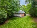 Aerial view of a lush backyard with a manicured lawn, deck, patio, and wooded surroundings at 4033 Weddington Manor Ct, Matthews, NC 28104