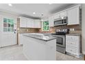 Bright kitchen featuring white cabinets, stainless steel appliances, and a granite island at 606 Deer Creek Dr, Matthews, NC 28105