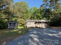 Wide shot of a gray house and outbuilding, with large trees in the background at 654 Old Nc 515 Hwy, Wadesboro, NC 28170