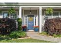Inviting entryway featuring a blue door, decorative wreath, and colorful potted plants at 7216 Old Valley Way, Harrisburg, NC 28075