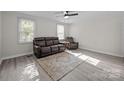 Bright living room featuring wood floors, neutral walls, ceiling fan, and comfortable brown leather furniture at 804 Allen Dr, Marshville, NC 28103