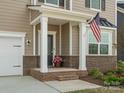 Covered front porch with brick accents, white columns, and an American flag at 1005 Cheviot Ct, Waxhaw, NC 28173