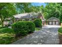 This exterior view highlights the driveway, lush landscaping, and detached two-car garage of the home at 1260 Piccadilly Dr, Charlotte, NC 28211