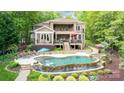 Expansive backyard featuring a luxurious pool, spa, stone terraces, and lush landscaping at 135 Sumter Dr, Mooresville, NC 28117