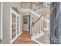 Elegant foyer featuring hardwood floors, staircase with white railings, and french doors leading to another room at 15000 Strathmoor Dr, Charlotte, NC 28277