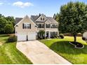 Charming two-story home boasts a lush green lawn, mature trees, and a convenient two-car garage at 1900 Birchbrook Ct, Harrisburg, NC 28075