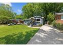 Quaint single-story home with a long driveway and lush green lawn, surrounded by mature trees and landscaping at 2933 Hilliard Dr, Charlotte, NC 28205