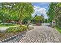 Community entrance featuring brick pillars, iron gates, mature landscaping, and a cobblestone drive at 4122 Banfield Pl, Charlotte, NC 28226