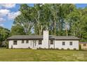 Charming white brick home with a well-manicured lawn and a classic chimney, nestled among mature trees at 6301 Vernedale Rd, Charlotte, NC 28212