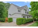 Side view of a beautiful white home with lush green landscaping, and a welcoming driveway at 7049 Sedgebrook W Dr, Stanley, NC 28164