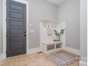 Functional mudroom featuring a built-in bench, hooks, and neutral tile flooring at 710 Morgan Park Dr, Charlotte, NC 28204