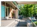 View of the front porch with a turquoise door, brick walls, and a seating area surrounded by lush greenery at 714 Larkhall Ln, Charlotte, NC 28211