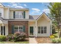 Charming townhome featuring a brick accent wall, green shutters, and well-maintained landscaping at 7718 Petrea Ln, Charlotte, NC 28227