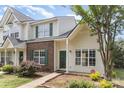 Charming townhome featuring a brick accent wall, green shutters, and lush landscaping at 7718 Petrea Ln, Charlotte, NC 28227