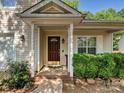 Inviting front entryway featuring a wood door, classic pillars, and manicured shrubs at 7923 Shiny Meadow Ln, Charlotte, NC 28215