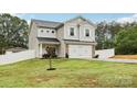 Inviting two-story home with a well-kept lawn, brick accents, and a two-car garage at 104 Trellis Ln, Troutman, NC 28166