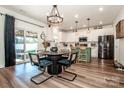 Bright eat-in kitchen with modern white cabinets, a large island, and a dining table by sliding glass doors at 104 Trellis Ln, Troutman, NC 28166