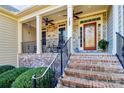 Inviting covered front porch with brick stairs, stone accents and decorative front door at 162 Kenway Loop, Mooresville, NC 28117