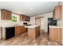 Well-lit kitchen featuring wood cabinets, a center island, black appliances, and durable vinyl flooring at 1785 Doe Ct, Iron Station, NC 28080