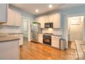 Well-lit kitchen with stainless steel appliances, white cabinetry, and hardwood floors at 3009 Thayer Dr, Waxhaw, NC 28173