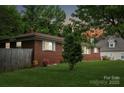 View of the back of a brick home with a wooden fence and some landscaping at 4623 Drifter Dr # 30, Charlotte, NC 28227