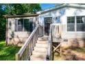 Close-up of the front porch featuring wooden stairs, a dark door with glass, and beige vinyl siding at 4920 Morrison Houser Trl # 2, Lincolnton, NC 28092