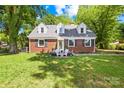 Charming brick home with manicured lawn and inviting front porch with chairs at 6012 Tuckaseegee Rd, Charlotte, NC 28208