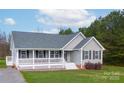 Well-maintained home with a welcoming front porch, gray siding, black shutters, and mature trees at 6300 Bill Sain Rd, Vale, NC 28168