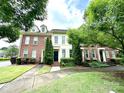 Attractive exterior view showcases townhomes with lush greenery, brick facade, and inviting entrances at 9832 Longstone Ln, Charlotte, NC 28277