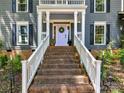Welcoming front porch with brick steps and a white railing leading to a charming light purple front door at 10024 Whitethorn Dr, Charlotte, NC 28277