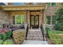 Inviting front porch with brick steps, elegant railing, and a charming light fixture above the wood and glass front door at 1614 Tarrington Way, Indian Trail, NC 28079