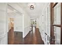 Bright hallway featuring hardwood floors, white wainscoting, crown molding, and paneled glass doors at 1614 Tarrington Way, Indian Trail, NC 28079