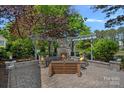 Beautiful outdoor stone fireplace has seating, custom pergola, and is surrounded by lush landscaping at 17924 River Ford Dr, Davidson, NC 28036