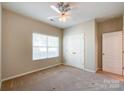 A cozy bedroom featuring a ceiling fan, natural light, and a double-door closet for ample storage at 1876 Yellow Daisy Dr, Matthews, NC 28104