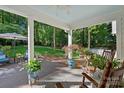 Relaxing covered patio with rocking chairs, potted plants, and view of a lush backyard at 2500 Little Cove Rd, Charlotte, NC 28270