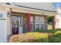 Inviting front porch featuring stone pillars, a red door, manicured bushes and large picture windows at 9588 Marquette Nw St, Concord, NC 28027
