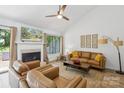 Cozy living room featuring a white fireplace, tan sofas, ceiling fan and a large window at 11216 Carmel Chace Dr, Charlotte, NC 28226