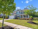 Beautiful gray two-story home featuring an attached two-car garage, a charming front porch and manicured lawn at 11931 The Ramble Dr, Huntersville, NC 28078