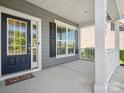 Inviting covered front porch featuring white columns, decorative windows and storm door with decorative glass at 11931 The Ramble Dr, Huntersville, NC 28078