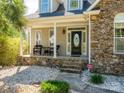 Inviting front porch with stone accents, featuring seating, and a decorative front door with an oval glass insert at 125 Mariner Pointe Ln, Mooresville, NC 28117